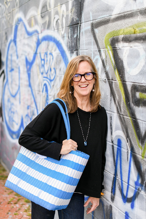 katie (owner/director of ixoq) standing against a graffiti covered wall with an xl cesta tote.