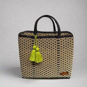 A medium-sized sand & black tote bag with a basket weave pattern and a decorative tassel.