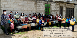 20+ women artisans gathered together in San Cristobal Totonicopan Guatemala, each holding a cesta tote bag. handwoven from recycled plastic cord. The  text on the image says 'we follow fair trade standards ~ working & connecting directly with women artisans & paying a fair wage for their work'
